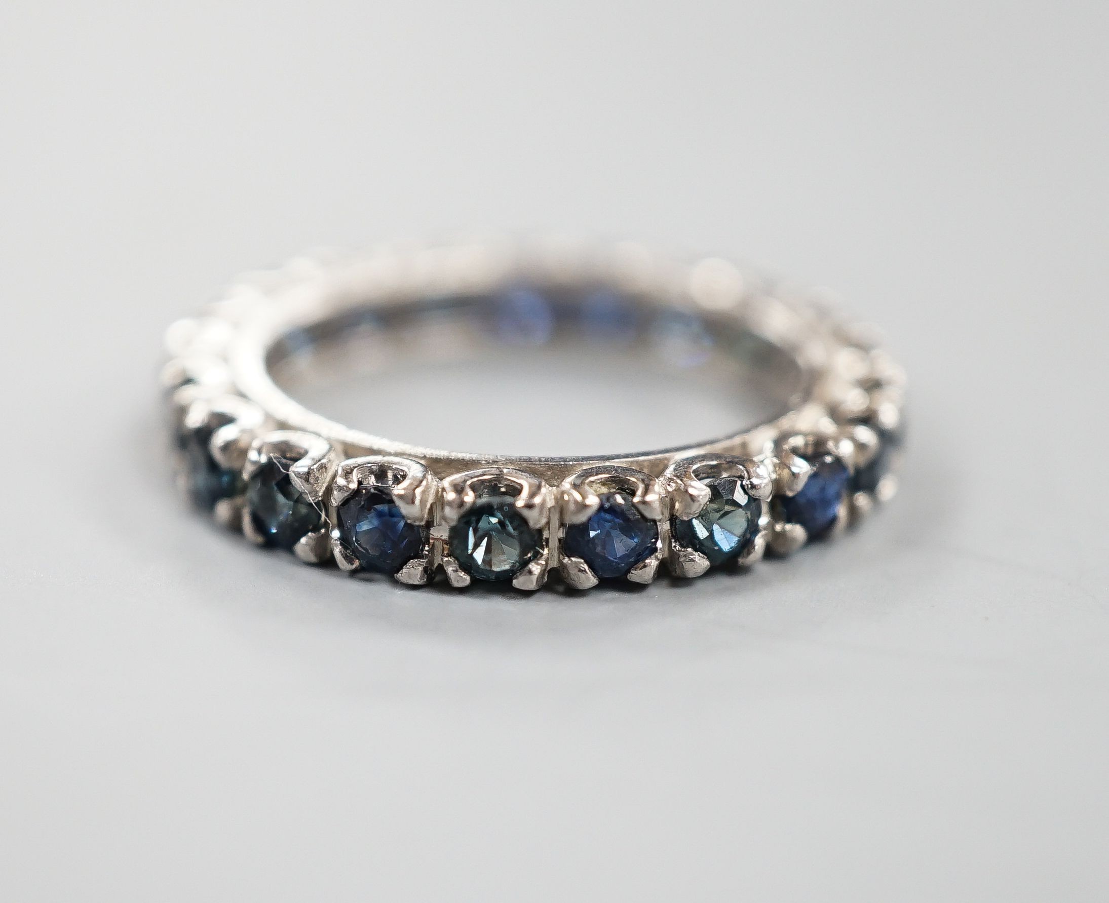 A white metal and sapphire set full eternity ring, size L, gross weight 3.4 grams.